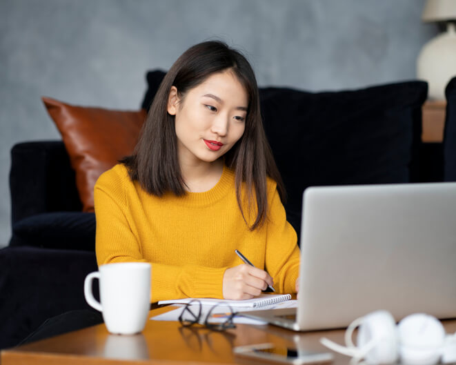 Woman at laptop with notepad