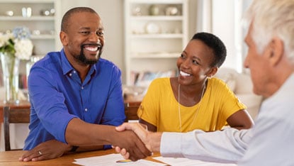 Happy couple shaking hands with an advisor