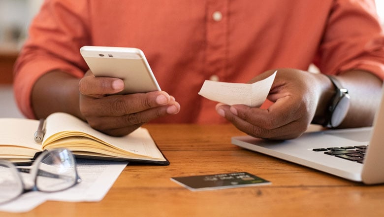 Hombre mirando el teléfono con recibo