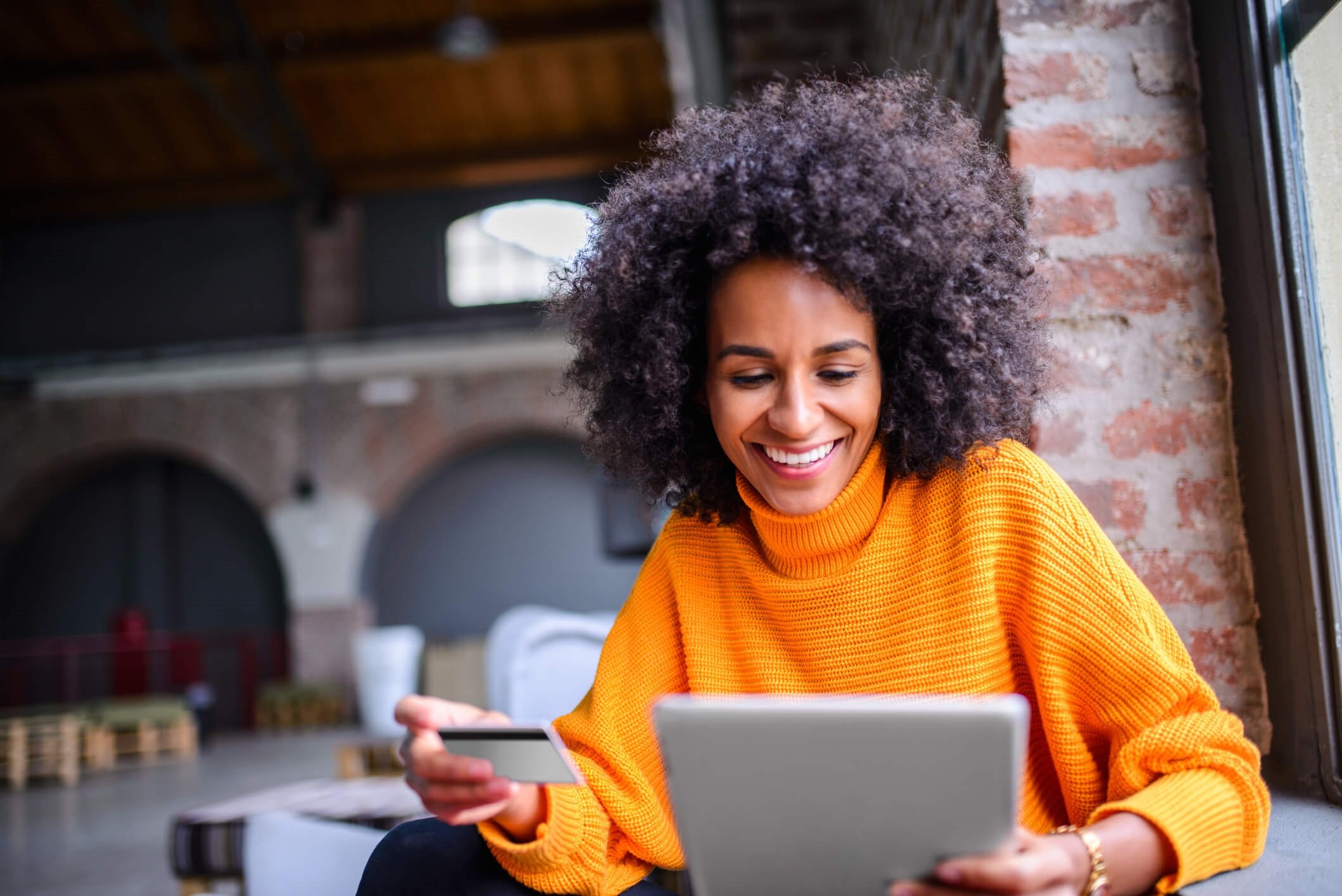 woman holding card looking at tablet