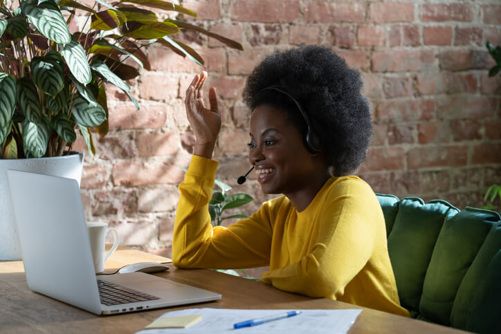 Woman in yellow sweater with headset on computer