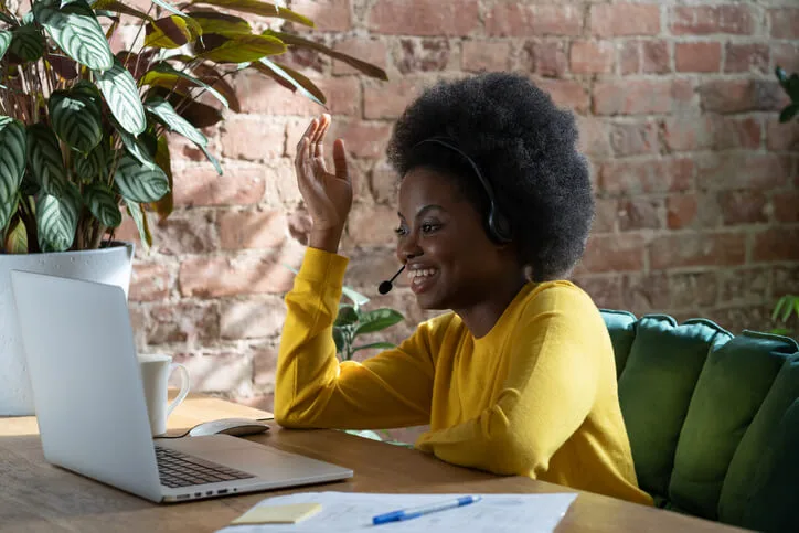 Woman in yellow sweater with headset on computer
