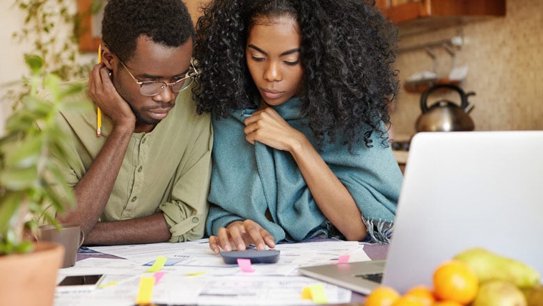 Man and woman at a desk with papers and a laptop