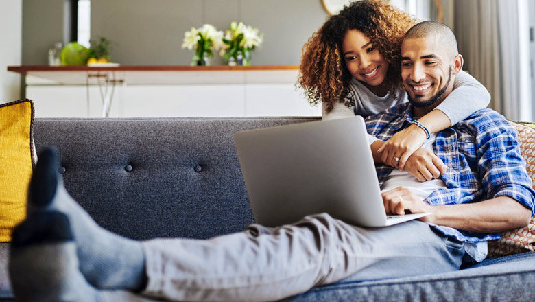 couple on couch looking at laptop