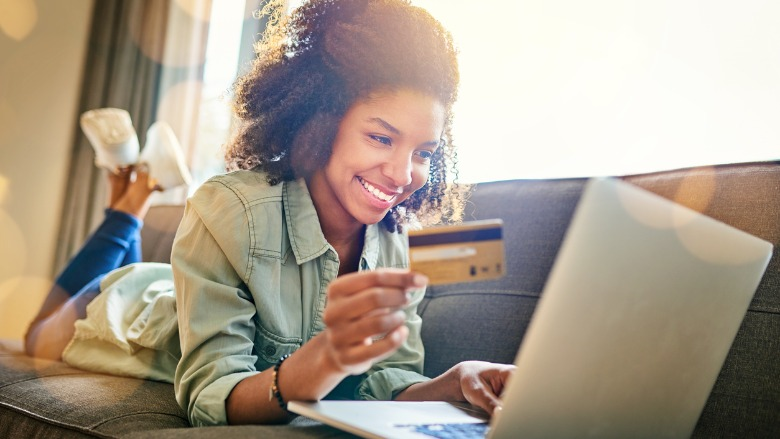 woman on couch using card to purchase online