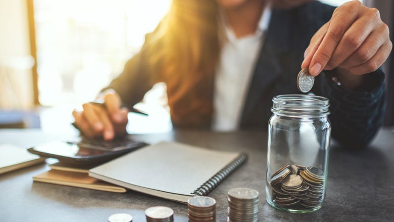 mujer arrojando monedas en un frasco
