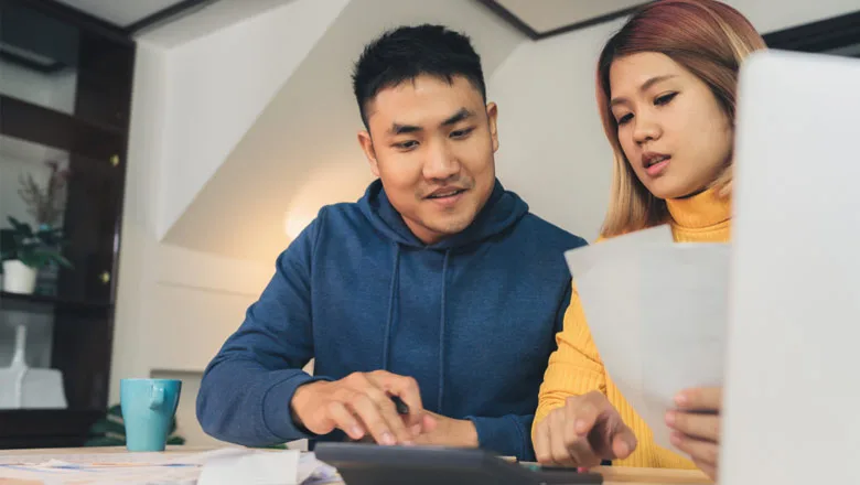 Couple at desk in front of computer with papers