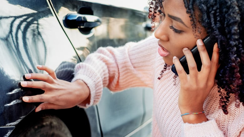 woman looking at a scratch on a car