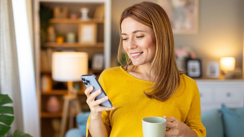 woman in yellow shirt with coffee cup and mobile phone