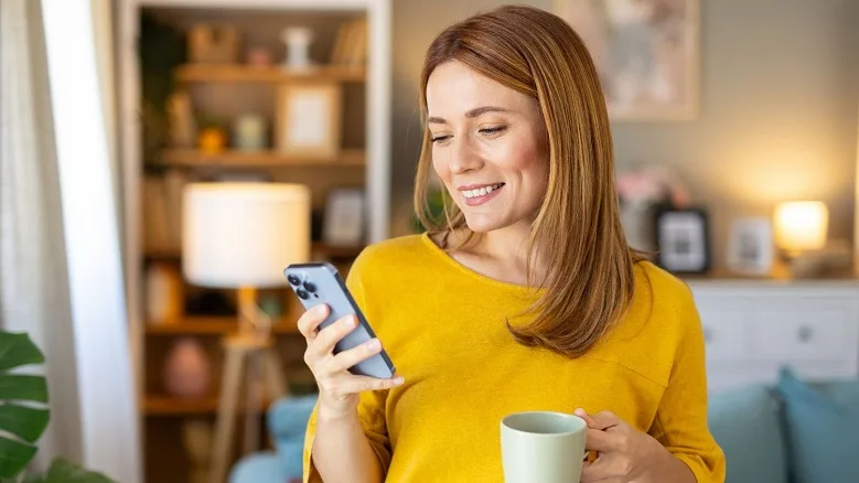 woman in yellow shirt with coffee cup and mobile phone