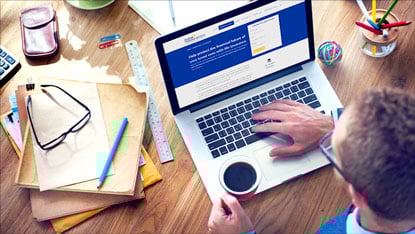 man at a desk with coffee and laptop