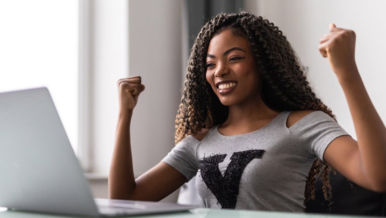 Young woman celebrating at her laptop