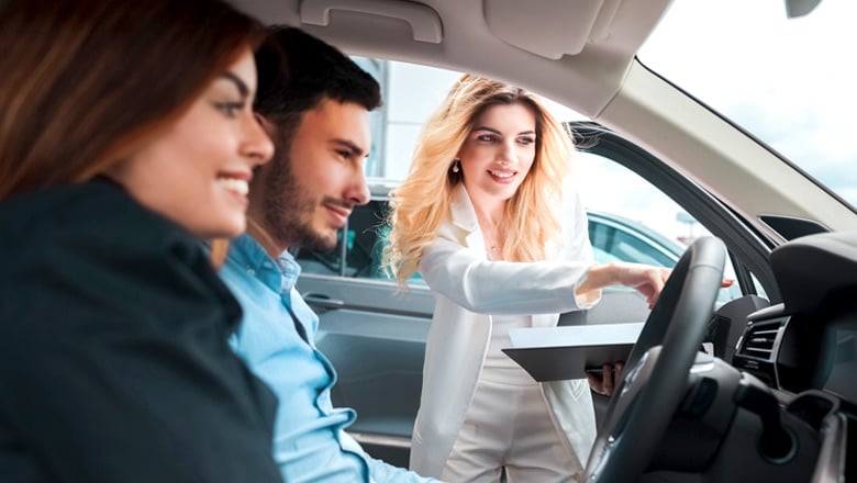 man and woman sitting in a new car