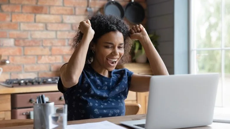 happy woman looking at laptop on desk