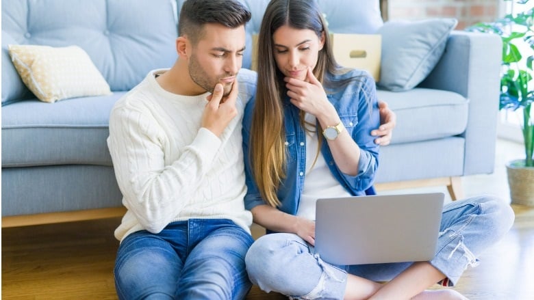 Pareja en una mesa mirando una computadora portáti