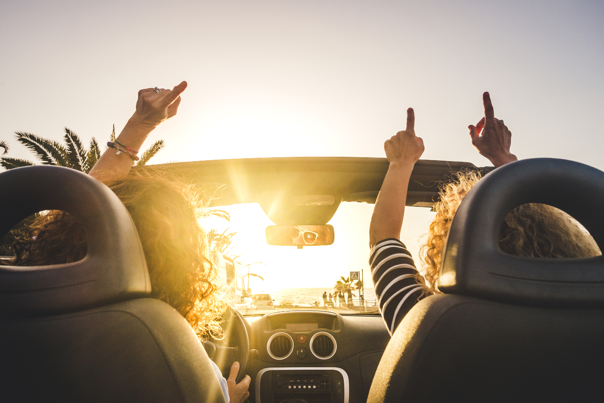 Two people in a convertible with a sunset