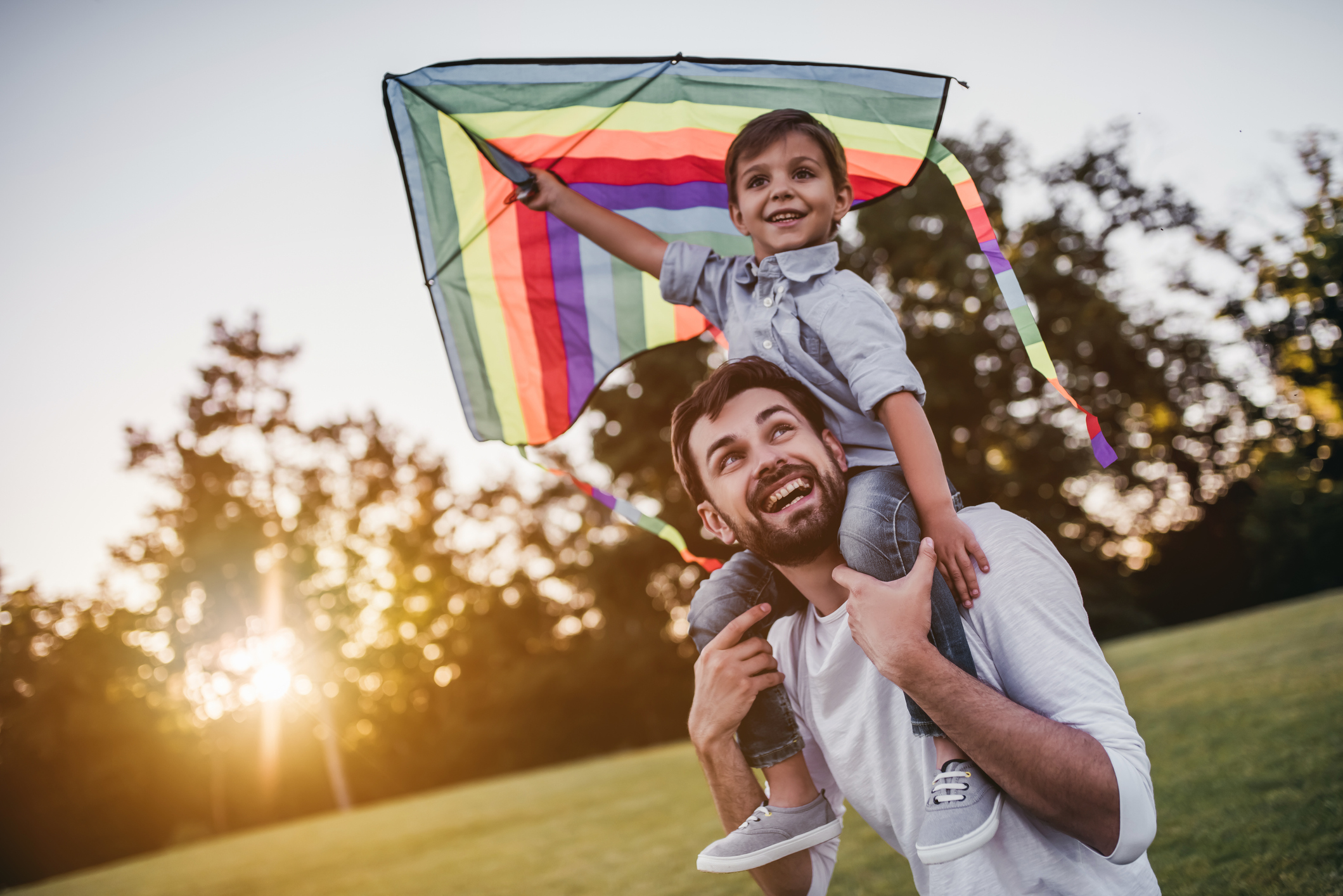 dad with young son on shoulders holding a kite