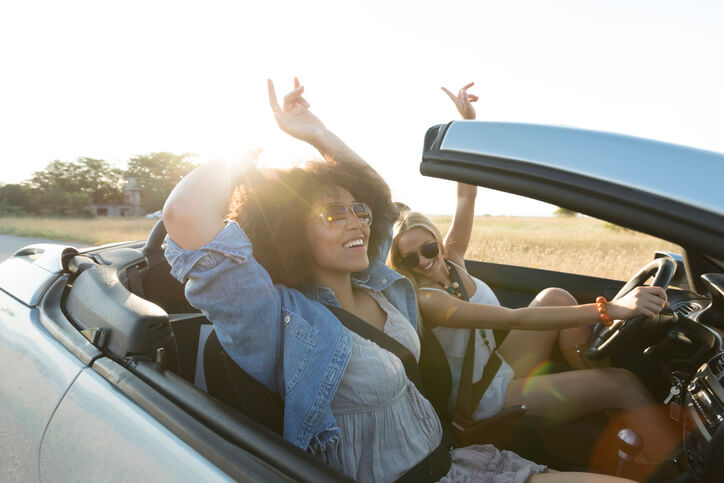 Two people in a convertible with a sunset