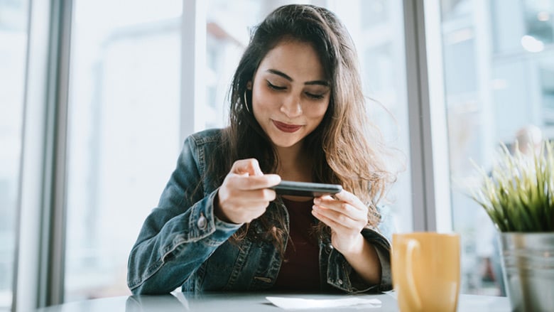 Woman in cafe depositing check with her phone