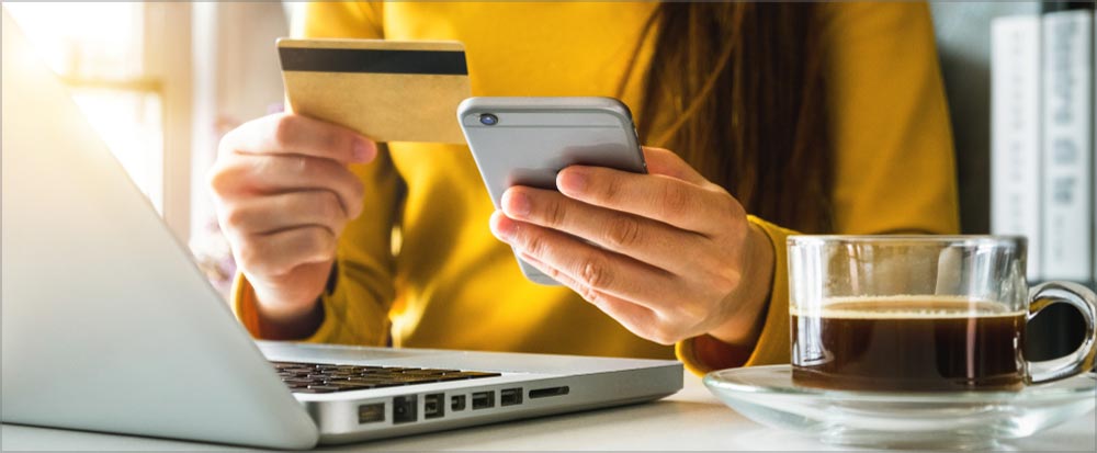 Woman at a laptop at a credit card and phone