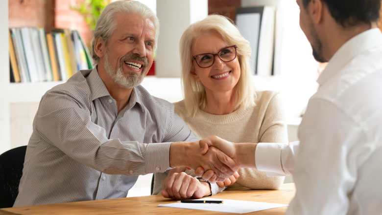 Couple sitting at desk shaking hands with advisor