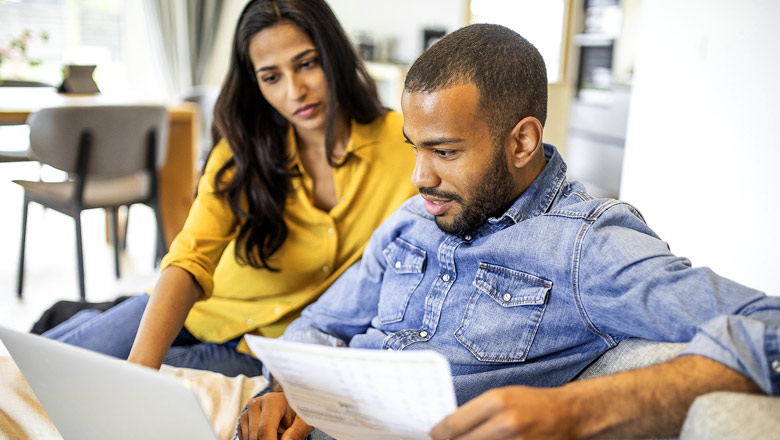 Couple on couch reviewing finances