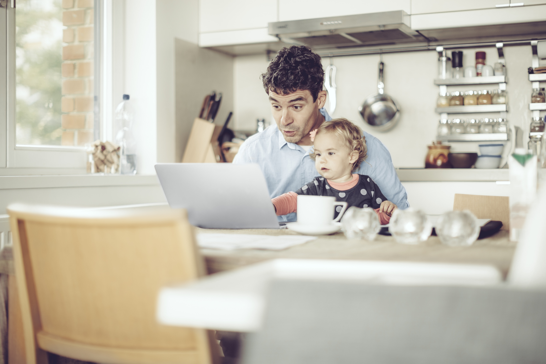 dad at table working with young daughter in lap