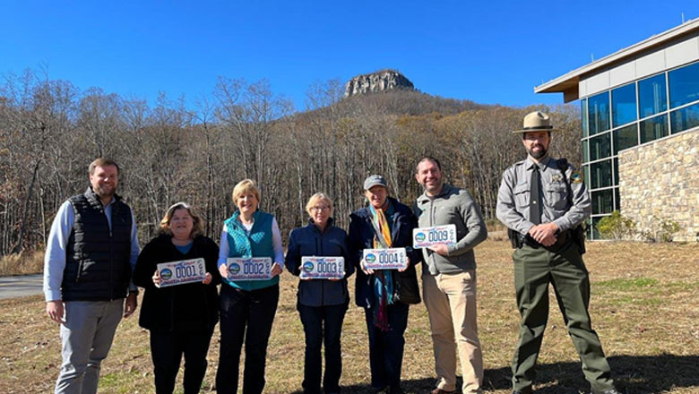 People posing with Pilot Mountain license plates