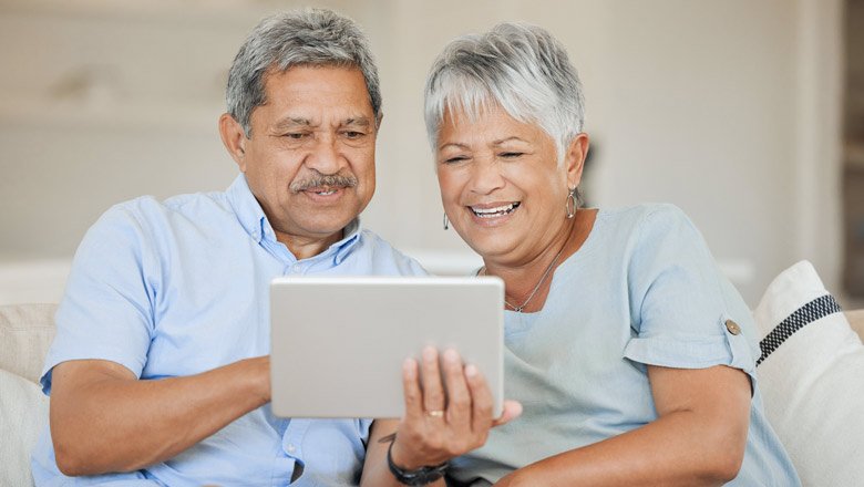 pareja de hispanos mayores en el sofá con tableta