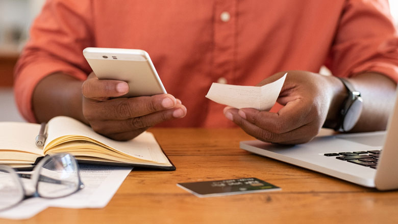 Man looking at phone with laptop open