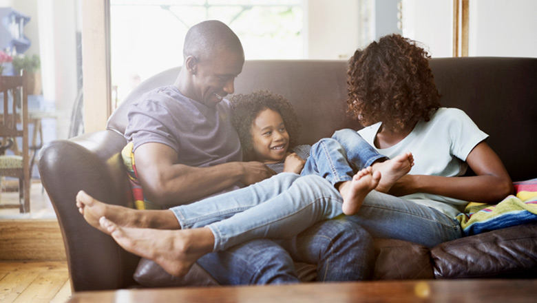 mom, dad and young daughter playing on couch