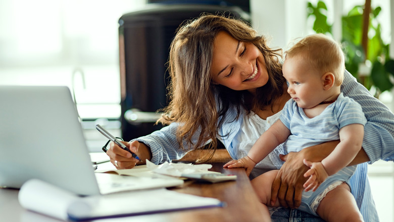 smiling mom holding baby doing paperwork