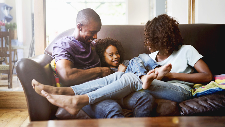 mom, dad and young daughter playing on couch