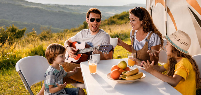 family eating outside next to RV in mountains