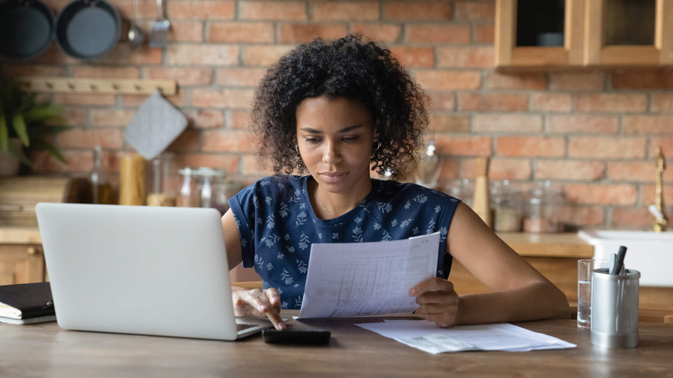Woman holding account statement with laptop