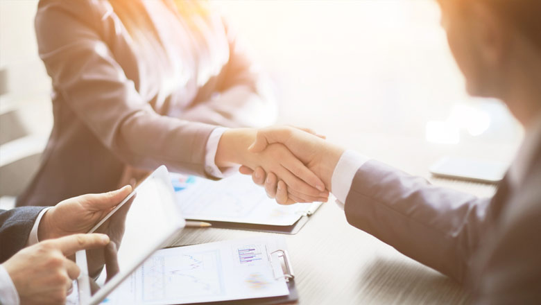 Man and woman shaking hands across business desk 