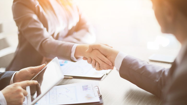 Man and woman shaking hands across business desk