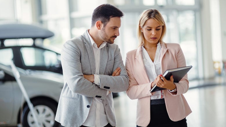 Man at auto dealership talking to a salesperson