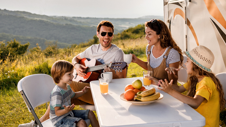family eating outside next to RV in mountains