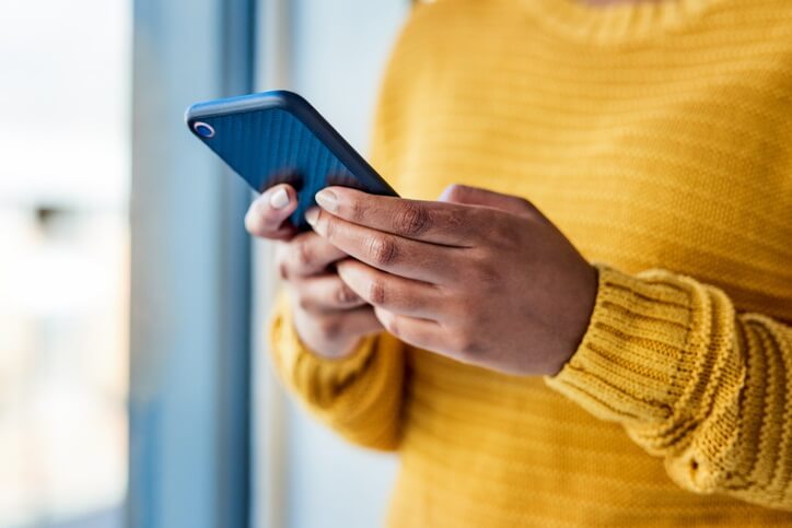 Person in yellow sweater holding cellphone