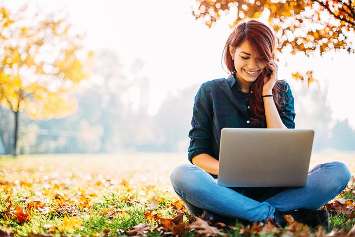 woman with laptop outside in the fall