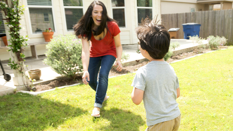 mom playing chase with son in backyard
