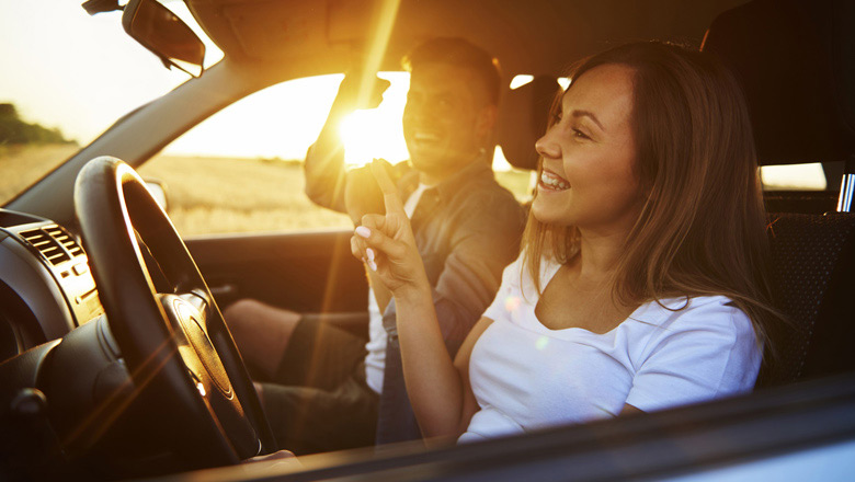 Happy couple in a car with a sunburst