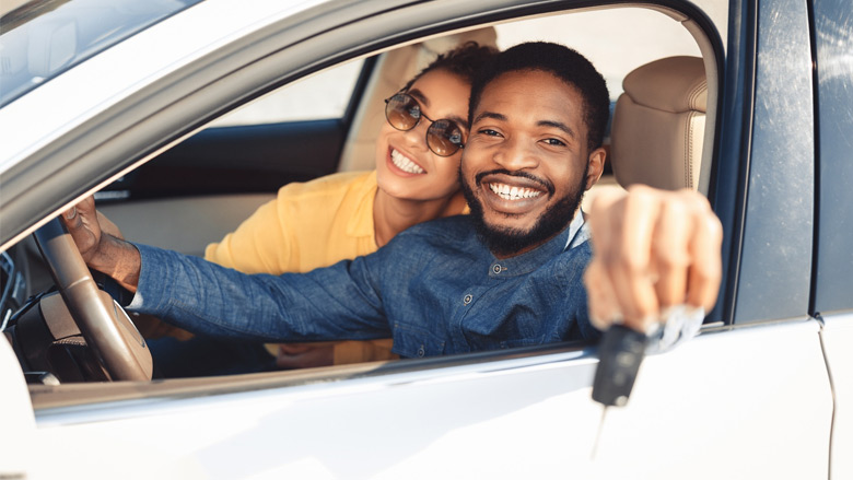Couple in a car smiling with keys in hand