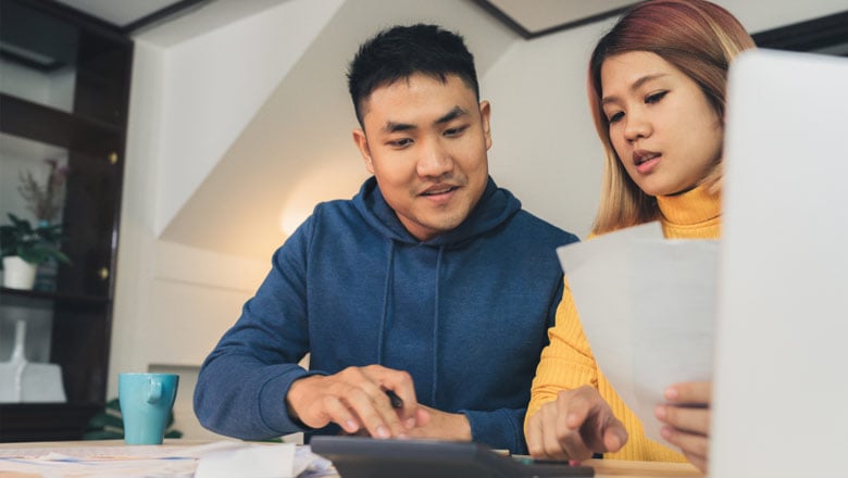 Couple at desk in front of computer with papers