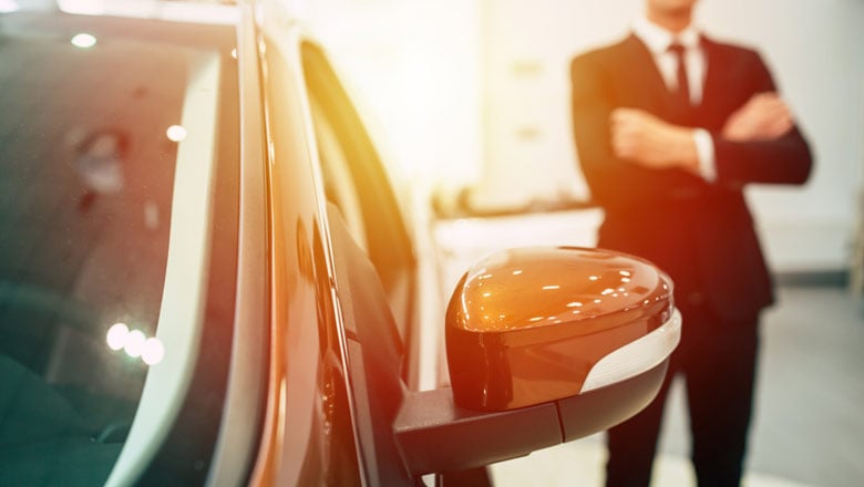 Man standing in car dealership, looking at a car