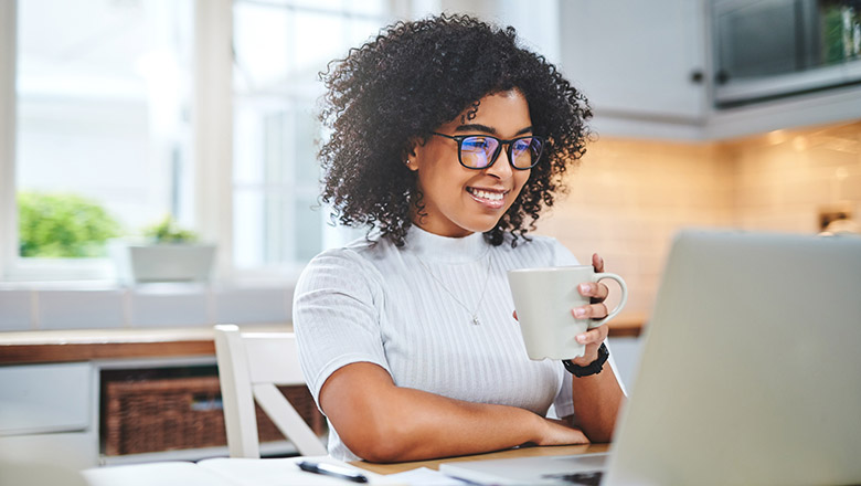 woman with coffee cup looking at computer