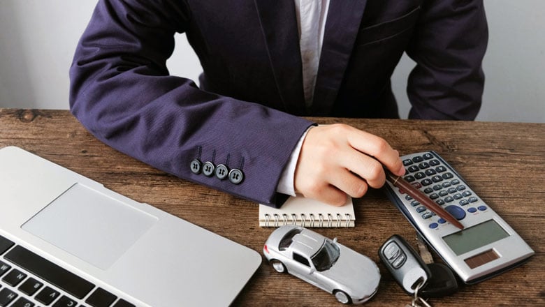 Man sitting behind desk with laptop, calculator an