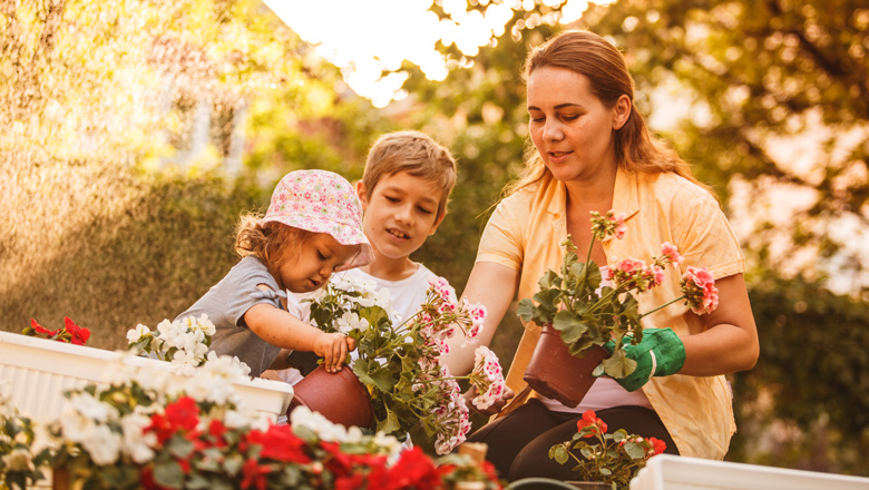 mom with two young kids planting flowers