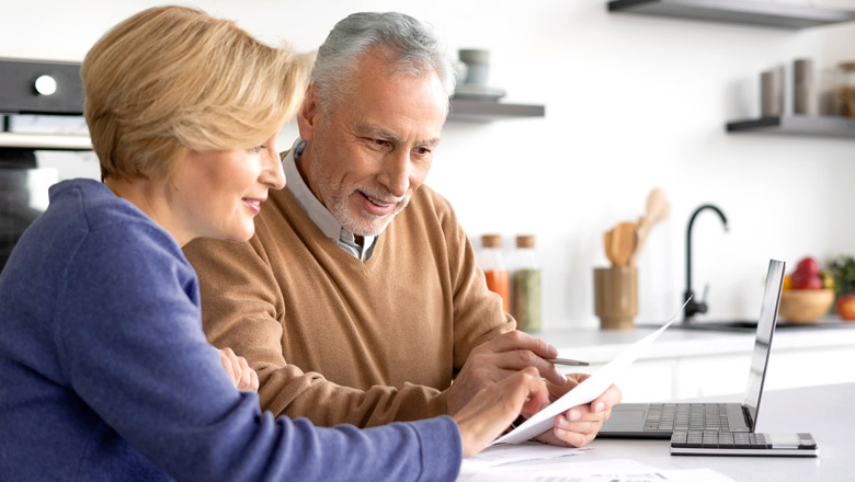 Couple sitting at a table with bills and laptop